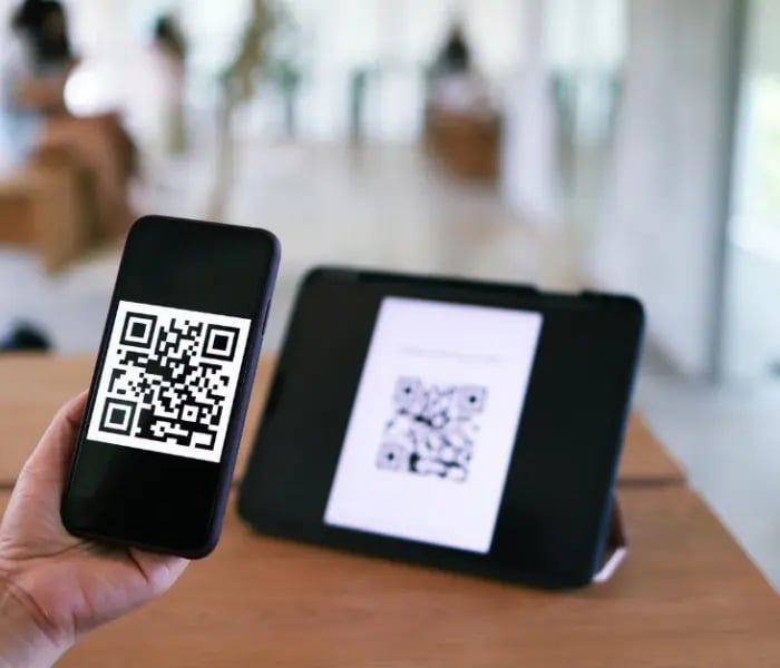 iPhoneでタブレットのQRコードを読み取る人 
